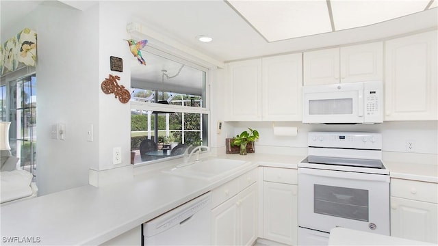 kitchen with white cabinets, white appliances, light countertops, and a sink