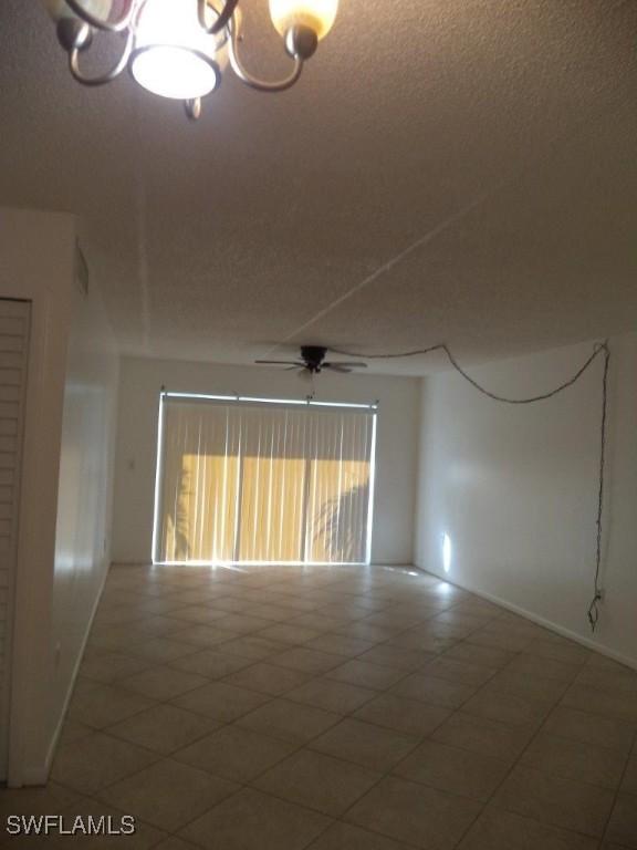 unfurnished room featuring ceiling fan with notable chandelier and a textured ceiling