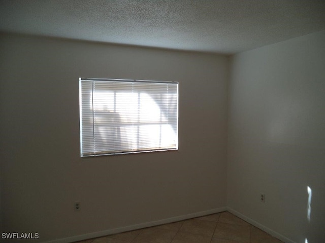 spare room with light tile patterned floors and a textured ceiling