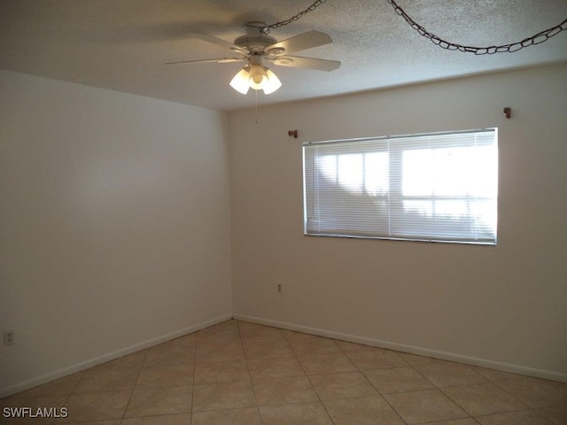 tiled empty room featuring ceiling fan and a textured ceiling