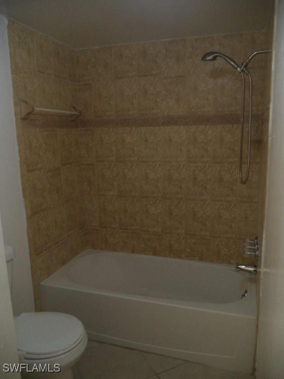 bathroom featuring tile patterned flooring, tiled shower / bath, and toilet