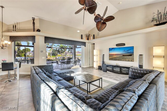 tiled living room with high vaulted ceiling and ceiling fan with notable chandelier