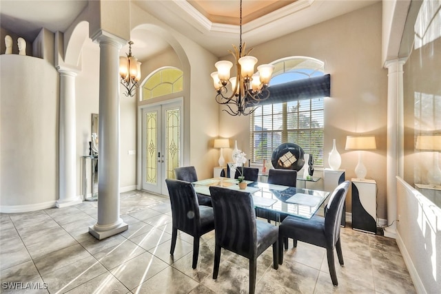 dining room featuring a notable chandelier, a raised ceiling, crown molding, french doors, and decorative columns