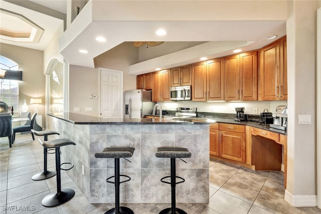 kitchen featuring stainless steel appliances, sink, a kitchen breakfast bar, vaulted ceiling, and light tile patterned floors