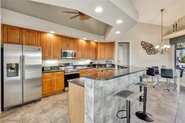 kitchen with appliances with stainless steel finishes, sink, hanging light fixtures, kitchen peninsula, and a breakfast bar