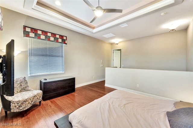 bedroom with ceiling fan, wood-type flooring, and a raised ceiling