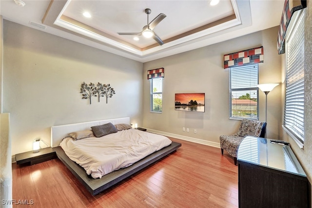 bedroom with a raised ceiling, ceiling fan, and hardwood / wood-style floors