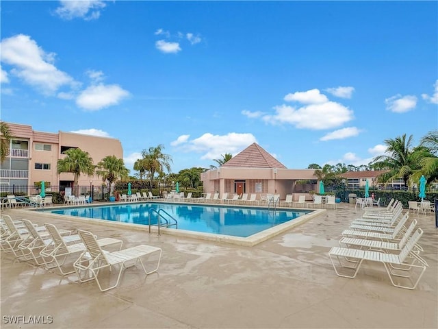 community pool with a patio area and fence