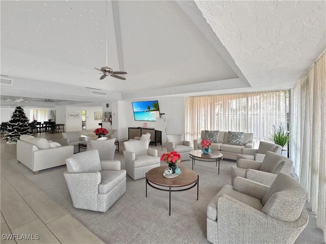 living room featuring visible vents, a raised ceiling, a textured ceiling, and ceiling fan