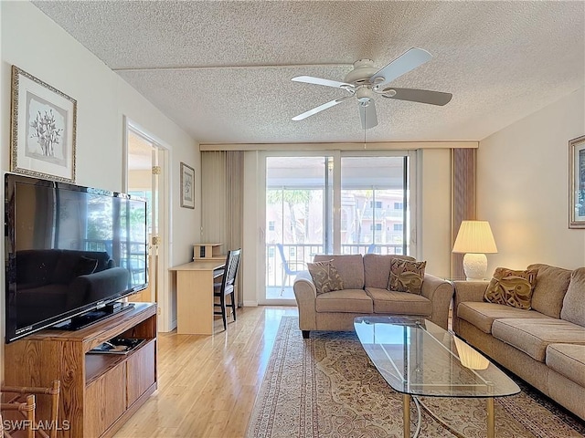 living room with a textured ceiling, light wood-style flooring, and a ceiling fan