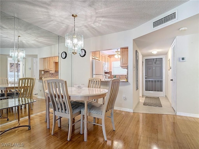 dining room with visible vents, an inviting chandelier, and light wood finished floors