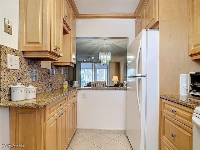 kitchen with light tile patterned floors, stone countertops, freestanding refrigerator, ornamental molding, and backsplash