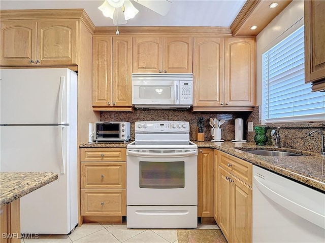 kitchen with stone counters, light brown cabinets, white appliances, and sink