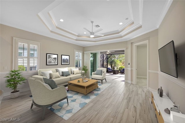 living room with ceiling fan, light hardwood / wood-style floors, crown molding, and a tray ceiling