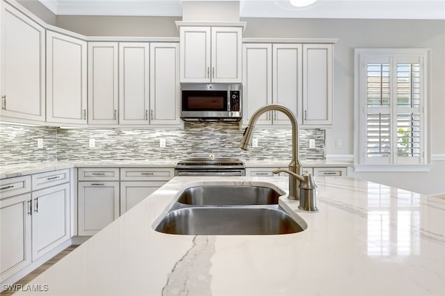 kitchen featuring light stone counters, white cabinetry, sink, and tasteful backsplash