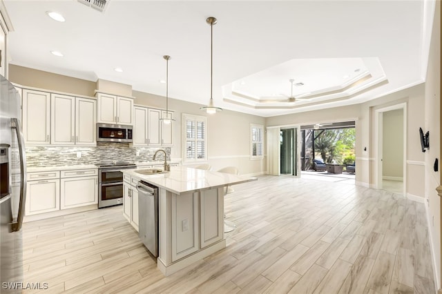 kitchen with appliances with stainless steel finishes, light stone counters, ceiling fan, sink, and hanging light fixtures