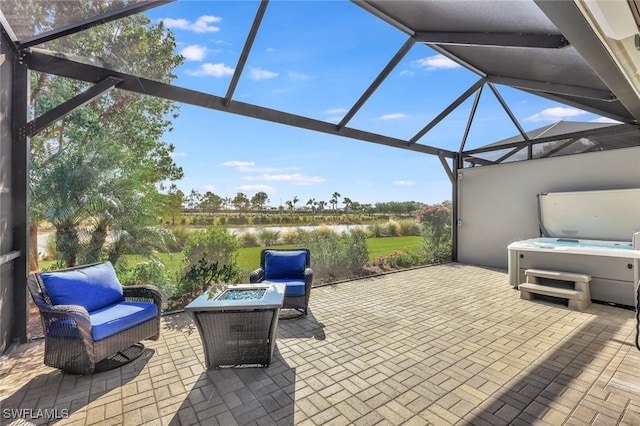 view of patio / terrace with a lanai, an outdoor fire pit, a water view, and a hot tub