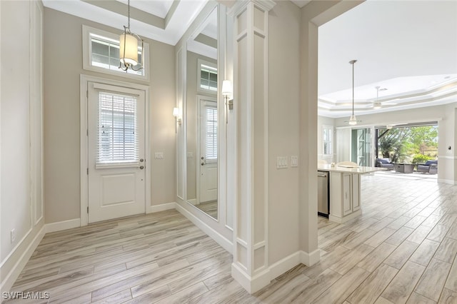 entryway featuring a raised ceiling, ceiling fan, light hardwood / wood-style flooring, and ornamental molding