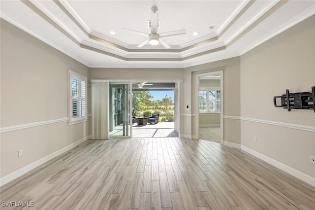 unfurnished room featuring ceiling fan, light hardwood / wood-style floors, a raised ceiling, and crown molding