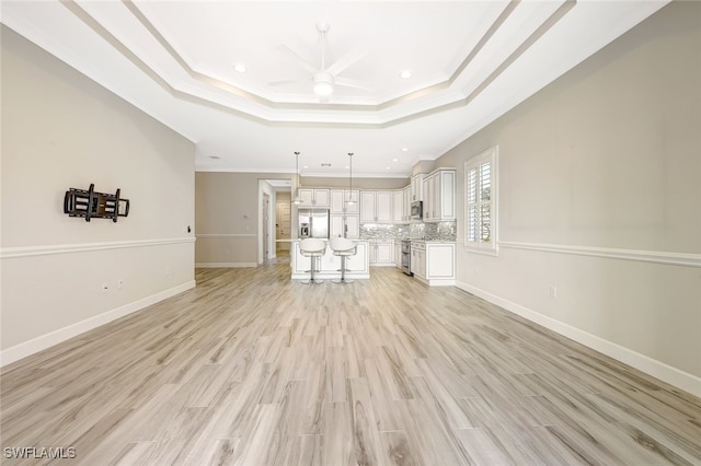 unfurnished living room featuring light hardwood / wood-style floors, a raised ceiling, ceiling fan, and crown molding