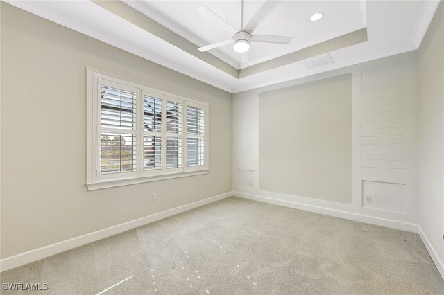 carpeted empty room with a tray ceiling, ceiling fan, and crown molding