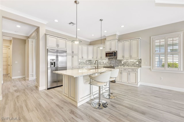 kitchen featuring pendant lighting, a kitchen island with sink, light wood-type flooring, light stone counters, and stainless steel appliances