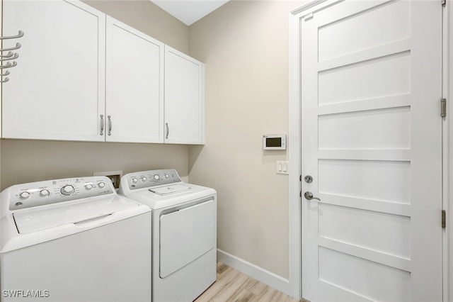 clothes washing area with cabinets, light hardwood / wood-style flooring, and washing machine and clothes dryer