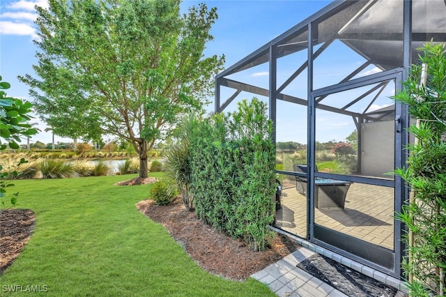 view of yard with a patio, a water view, and glass enclosure