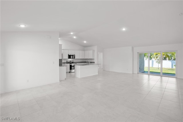 unfurnished living room featuring light tile patterned floors, vaulted ceiling, and sink