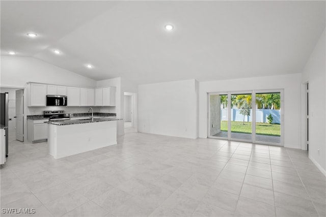 kitchen featuring lofted ceiling, a center island with sink, dark stone countertops, white cabinetry, and stainless steel appliances