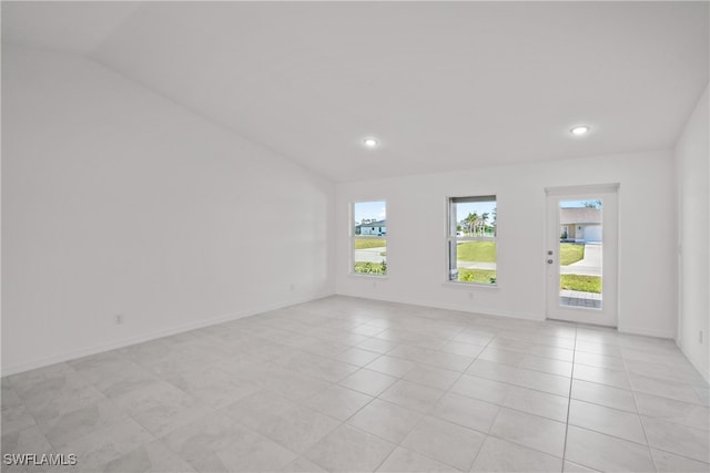 tiled spare room featuring lofted ceiling