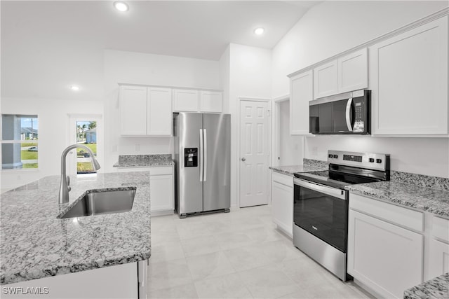 kitchen with light stone countertops, sink, vaulted ceiling, white cabinets, and appliances with stainless steel finishes