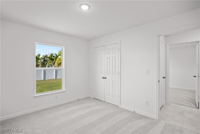 unfurnished bedroom with light colored carpet and a closet