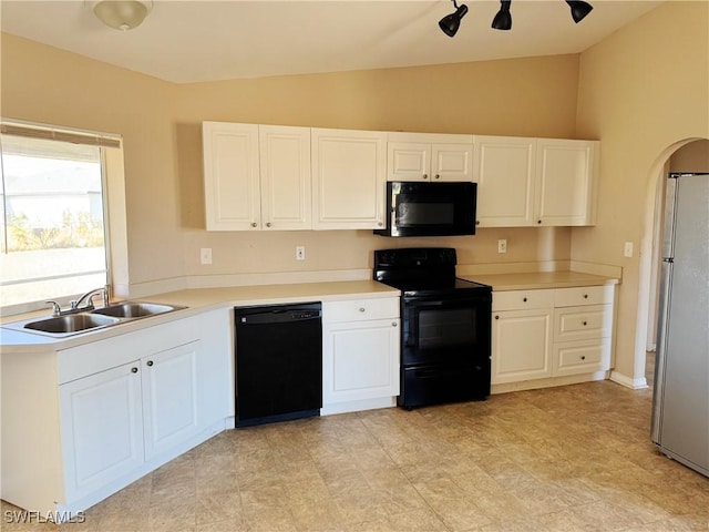 kitchen featuring sink, white cabinets, black appliances, and vaulted ceiling