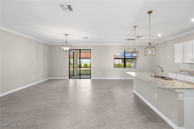 kitchen featuring white cabinets, light stone counters, sink, and hanging light fixtures