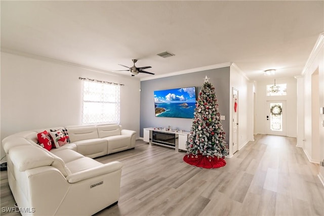 living room featuring hardwood / wood-style flooring, ceiling fan with notable chandelier, and ornamental molding