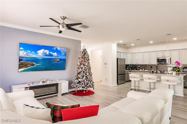 living room with ceiling fan, ornamental molding, and light hardwood / wood-style flooring