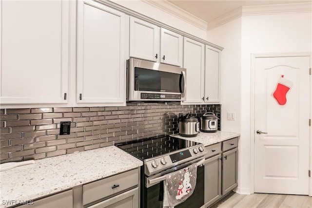 kitchen featuring backsplash, crown molding, light hardwood / wood-style flooring, light stone countertops, and stainless steel appliances