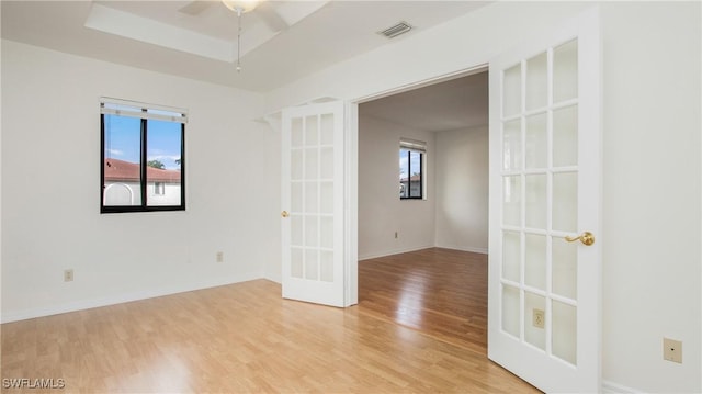 unfurnished room with ceiling fan, light hardwood / wood-style flooring, a healthy amount of sunlight, and french doors