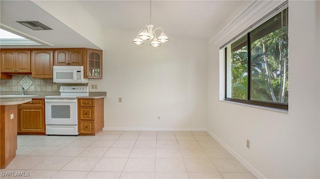 kitchen featuring decorative backsplash, white appliances, decorative light fixtures, an inviting chandelier, and lofted ceiling