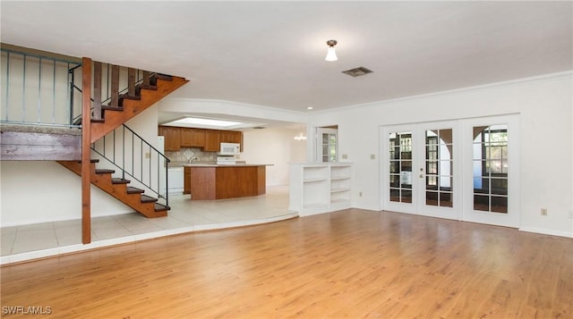 unfurnished living room featuring french doors, light hardwood / wood-style flooring, and ornamental molding