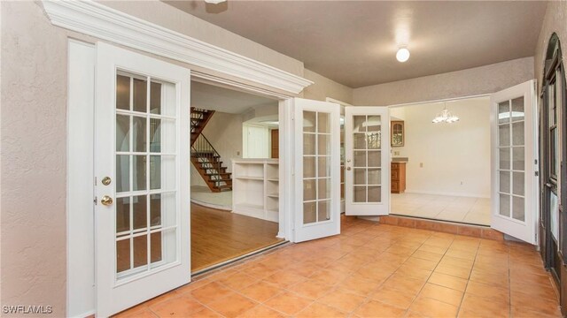 entryway with tile patterned flooring, french doors, and an inviting chandelier