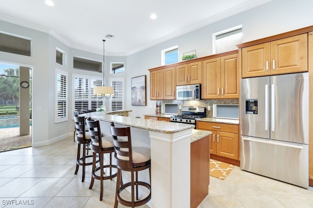 kitchen with light stone countertops, stainless steel appliances, pendant lighting, a kitchen bar, and ornamental molding