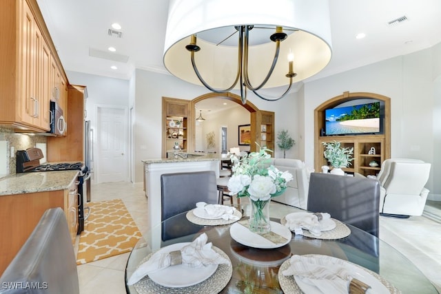 tiled dining room featuring built in features, ornamental molding, and a notable chandelier