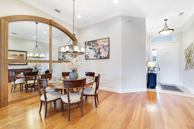 dining space with light hardwood / wood-style flooring, crown molding, and a notable chandelier