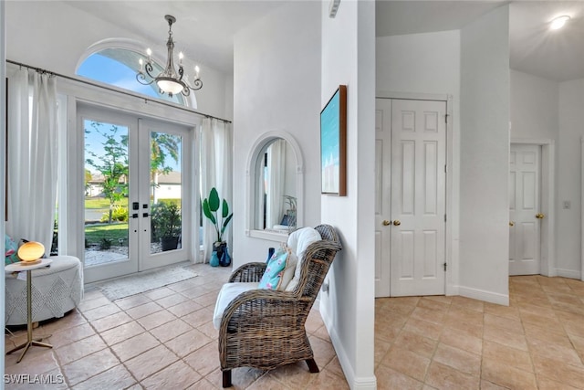 foyer entrance with french doors, high vaulted ceiling, light tile patterned flooring, and an inviting chandelier