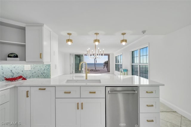 kitchen with pendant lighting, backsplash, white cabinets, sink, and stainless steel dishwasher