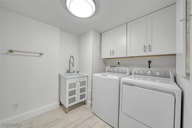 laundry area with light hardwood / wood-style flooring, cabinets, sink, and washing machine and clothes dryer