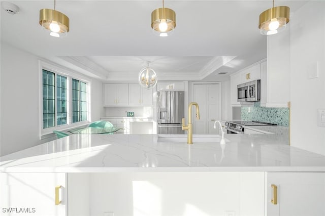 kitchen with white cabinets, hanging light fixtures, appliances with stainless steel finishes, and a tray ceiling