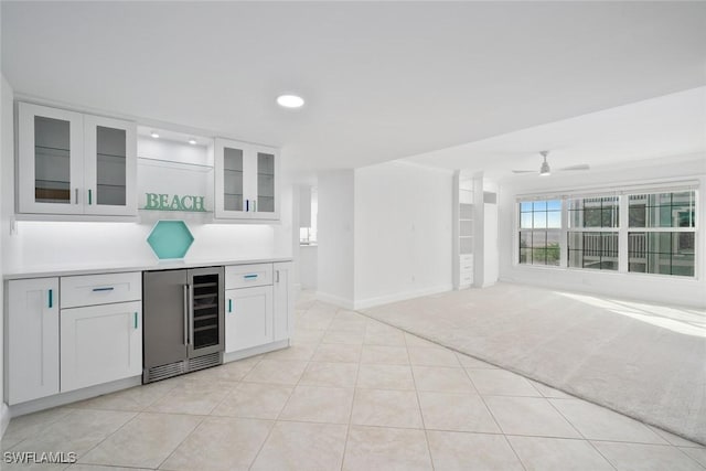 bar featuring white cabinetry, wine cooler, ceiling fan, and light colored carpet